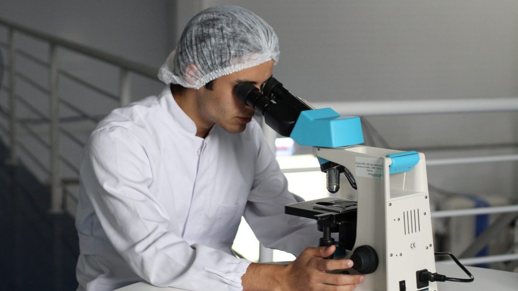 lucas-vasques-453684-unsplash-e1558491204899-1024×576 male looking through a microscope